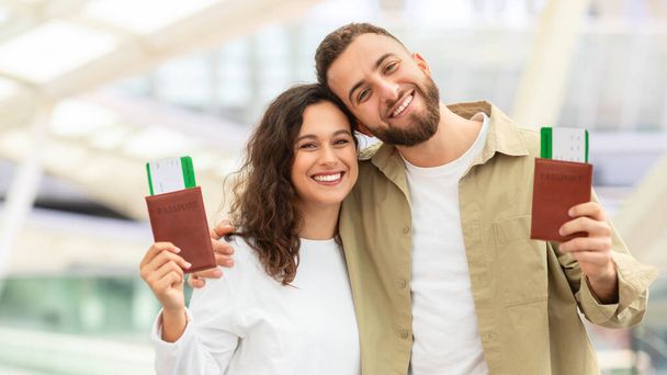 Viajeros felices. Retrato de pareja joven con pasaportes y entradas posando en el aeropuerto, alegre sonriente millennial hombre y mujer disfrutando viajando juntos, listo para el viaje de vacaciones, primer plano - Foto, Imagen
