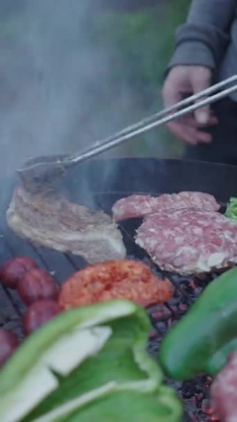 Gros plan de l'homme en utilisant des pinces de cuisson pour retourner la viande - plan au ralenti - Vidéo verticale FullHD - Séquence, vidéo