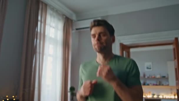 Muscular guy boxing at home closeup. Energetic young boxer practicing hand kicks at morning workout. Active handsome man in t-shirt training body strength in apartment. Enthusiastic athlete warming up - Footage, Video