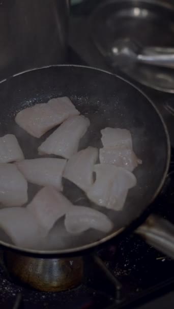 Zblízka pohled na kousky bílých ryb plamenované ve smažící pánvi - FullHD Vertikální video - Záběry, video
