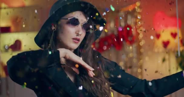 Attraente giovane donna in occhiali da sole e cappello che balla a casa durante la festa di Galentines - Filmati, video