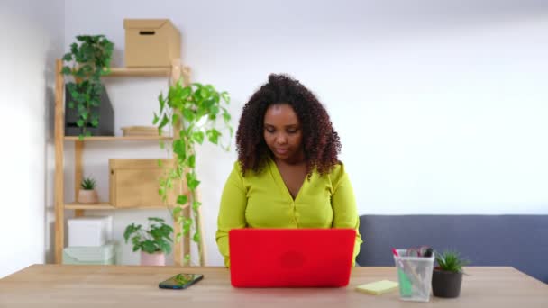 Młoda Afrykanka używająca laptopa w biurze. Właścicielka małego biznesu, pracująca na biurku w miejscu pracy. Przedsiębiorcy i przedsiębiorcy - Materiał filmowy, wideo