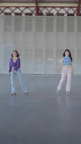 Trois jeunes femmes patinent à roulettes vers la caméra tout en tenant un pied - Vidéo verticale FullHD - Séquence, vidéo