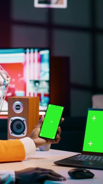 Verticale Video Afro-Amerikaanse meisje maakt gebruik van smartphone en pc met greenscreen, op zoek naar moderne apparaten met dezelfde geïsoleerde mockup template op het display. Jonge vrouw controleert copyspace schermen - Video