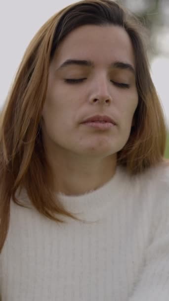 Mujer joven con los ojos cerrados rueda su cuello al aire libre, cerrar slomo disparo - 1080 Vídeo vertical - Imágenes, Vídeo