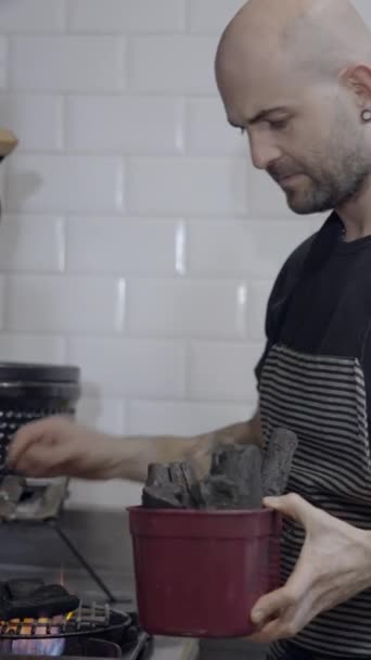 Chef zet houtskool op rooster in restaurant keuken, zijaanzicht - FullHD Verticale video - Video