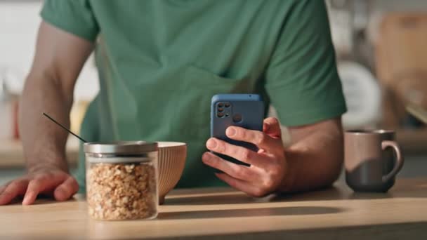 Comer mãos de homem segurando smartphone na cozinha closeup. Um bonitão focado a enviar mensagens de telemóvel a sentir-se feliz em casa. Freelancer morena sorridente conversando celular no apartamento leve sozinho - Filmagem, Vídeo