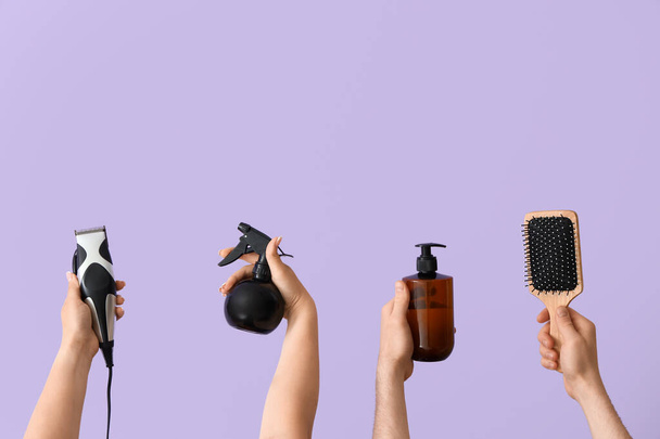 Muchas manos con diferentes suministros de peluquería sobre fondo lila - Foto, Imagen
