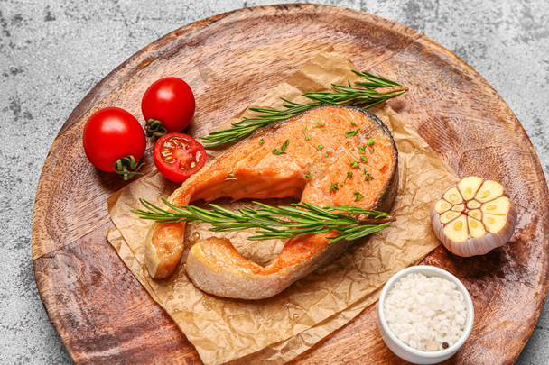 Тарелка вкусного стейка из лосося с помидорами и чесноком на сером фоне - Фото, изображение