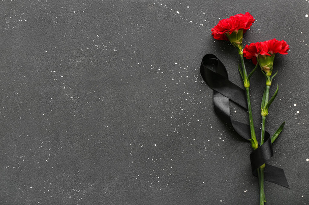 Kaunis neilikka kukkia musta hautajaisnauha tumma tausta - Valokuva, kuva