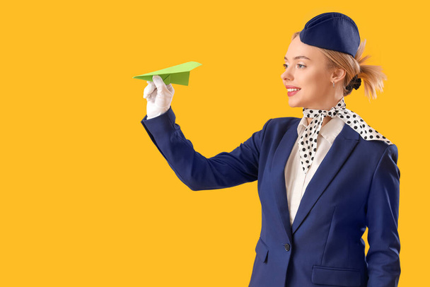 Молодий стюардеса з паперовою площиною на жовтому тлі - Фото, зображення
