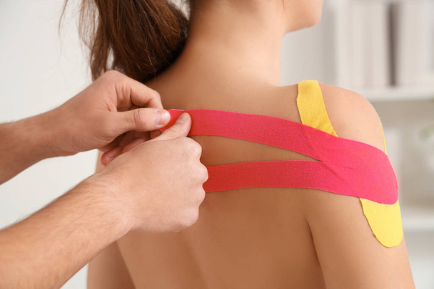Mannelijke fysiotherapeut plakt tape op de rug van de vrouw in revalidatiecentrum, close-up - Foto, afbeelding