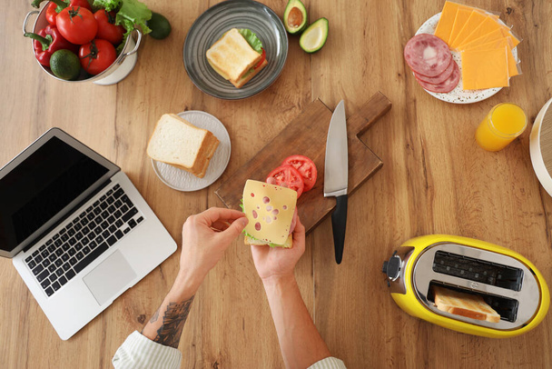 キッチンでトーストからおいしいサンドイッチを作る若者, トップビュー - 写真・画像