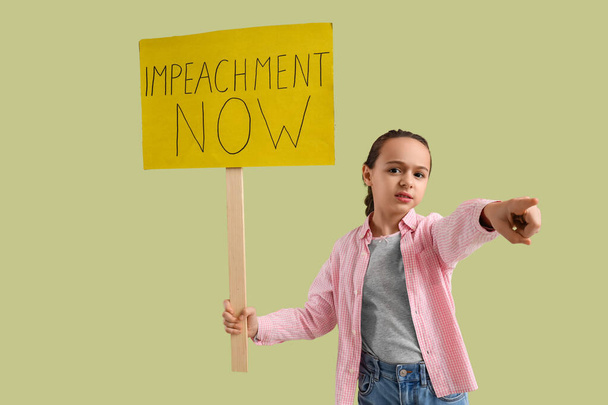 Protesting little girl holding placard with text IMPEACHMENT NOW and pointing at viewer on green background - Photo, Image