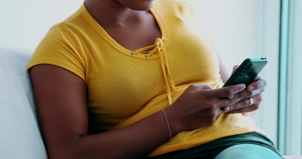Eine junge schwarze Frau schreibt SMS, Hände in Großaufnahme tippen entspannt in gelber Kleidung auf das Smartphone. Zwanziger Person afrikanischer Abstammung - Filmmaterial, Video