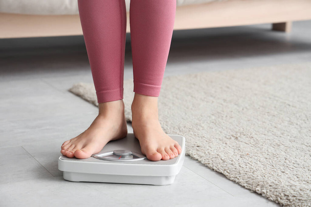 Young woman standing on scales at home. Weight loss concept - Photo, Image
