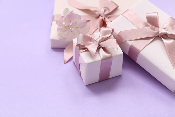 Geschenkschachteln und schöne Hortensienblüten auf fliederfarbenem Hintergrund. Internationaler Frauentag - Foto, Bild