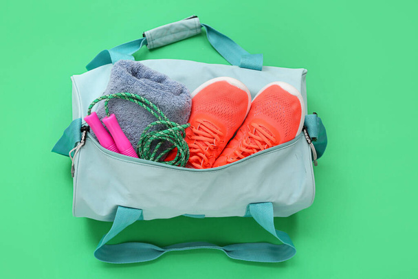 Sportovní taška se sportovním oblečením a tenisky na zeleném pozadí - Fotografie, Obrázek