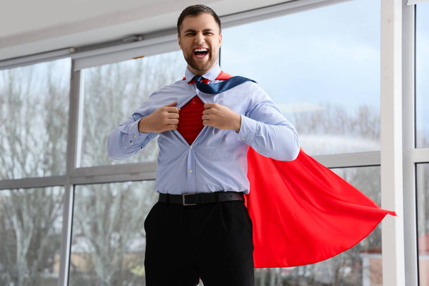 Wütender Superhelden-Geschäftsmann reißt sein Hemd am Fenster seines Büros herunter - Foto, Bild