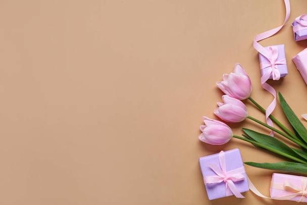 Состав с подарочными коробками и розовыми тюльпанами на бежевом фоне. Вид сверху - Фото, изображение
