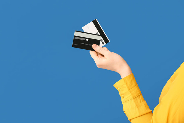 Vrouwelijke hand met creditcards op blauwe achtergrond - Foto, afbeelding