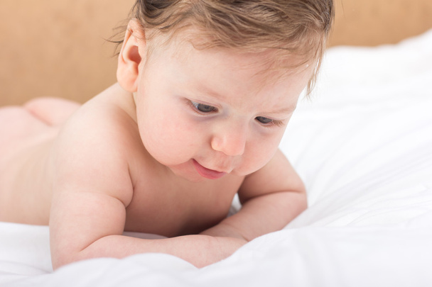 Портрет голого ребёнка. Ребенок на белой кровати. Симпатичный мальчик. улыбающийся ребенок
 - Фото, изображение