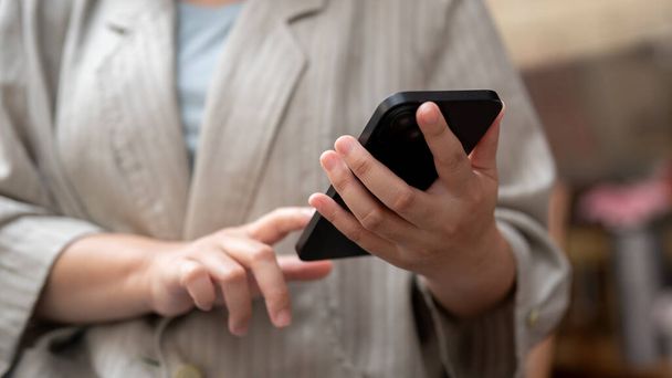 Una foto recortada de una mujer de negocios usando su teléfono inteligente, respondiendo a mensajes o leyendo artículos en línea. conceptos de personas y tecnología inalámbrica - Foto, Imagen
