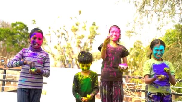 Niños indios felices jugando colores, sonriendo con colores en la cara de niños asiáticos celebrando Holi. Concepto para el festival indio Holi. Niños brillantes untados en polvo de color - Imágenes, Vídeo