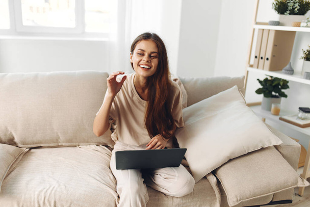 Mosolygó nő Szabadúszó laptop a kényelmes nappaliban, élvezi az online munka és kommunikáció - Fotó, kép