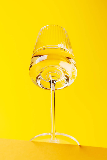 シャンパンエレガンス:鮮やかな黄色の背景に輝くワインとガラス. コピースペースを使って - 写真・画像