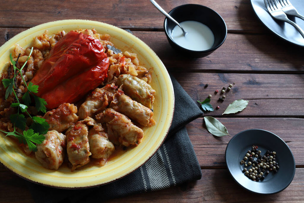 Stuffed cabbage rolls and pepper with chopped meat or vegetables and rice on rustic wooden table. Overhead view. - Photo, Image