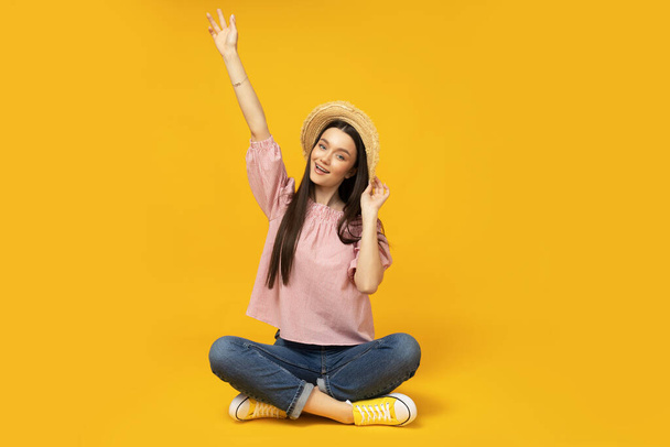 Young girl with a straw hat on a yellow background - Photo, Image