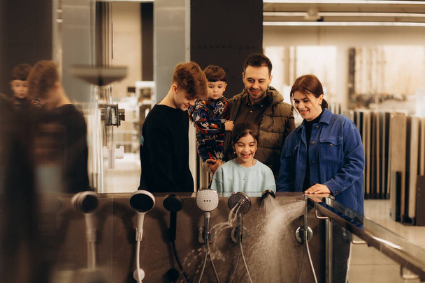 a big family chooses a shower system in a store - Foto, Bild