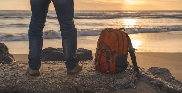 Bärtiger Mann mit Rucksack entspannt sich allein am Meer an einem heißen, sonnigen Tag bei Sonnenuntergang. Lebensstilkonzept Reisen - Foto, Bild
