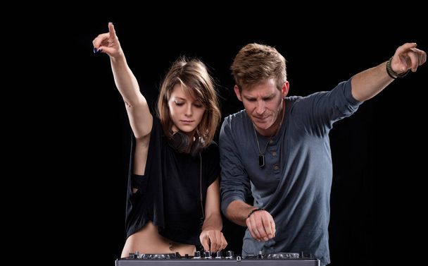 männliche und weibliche DJ teilen einen unbeschwerten Moment, lächelnd über das Musikmischpult in Kameradschaft - Foto, Bild