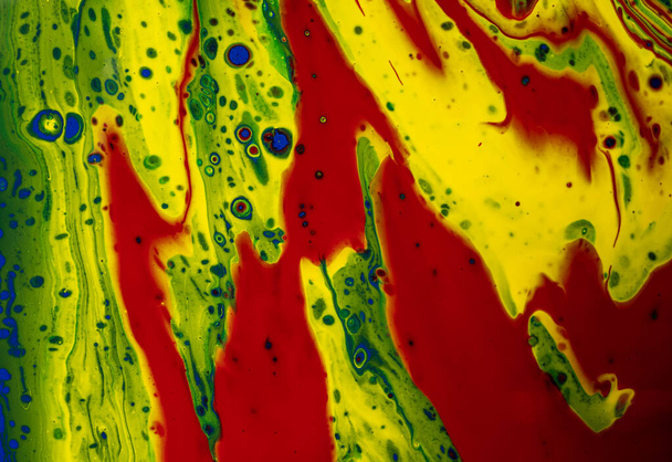 Close-up van een kleurrijk abstract schilderij met rode, gele en groene penseelstreken op een witte achtergrond - Foto, afbeelding
