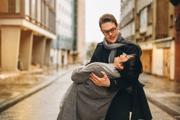 Knappe man en mooie vrouw knuffelen elkaar als ze lopen rond de stad, het hebben van leuke tijd, lifstyle foto - Foto, afbeelding