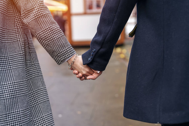 közelről kéz a kézben férfi és én nő ölelés egymást, ahogy sétálnak a városban, szórakozás idő, életstílus fotó - Fotó, kép