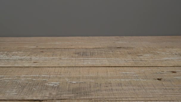 Gele maskertape rolt langs een houten oppervlak op een grijze achtergrond. Video. - Video