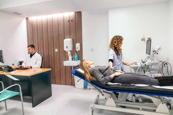 Un patient subissant une échographie avec des professionnels de la santé attentifs dans une salle de clinique bien équipée. - Photo, image