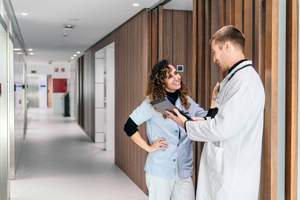 Medico e infermiere conversano su un blocco appunti in un moderno ospedale. - Foto, immagini