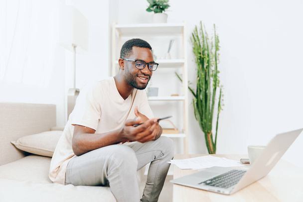 Glimlachende Afro-Amerikaanse man aan het werk op Laptop in Modern Home Office - Foto, afbeelding
