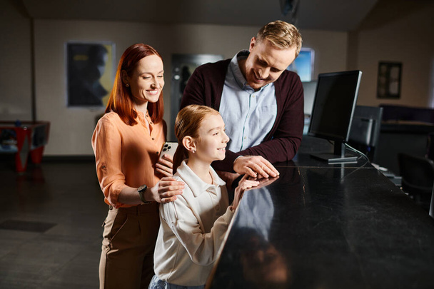 Mies, nainen ja lapsi seisovat yhdessä hymyillen ja nauttien elokuvasta onnellisena perheenä.. - Valokuva, kuva