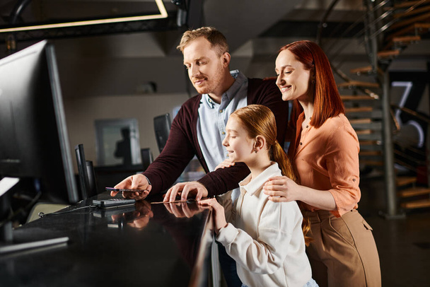 Ein Mann und zwei Frauen beschäftigen sich mit einem Computerbildschirm und zeigen Neugier und Zusammenarbeit in einem lebendigen Moment gemeinsamer Erkundung. - Foto, Bild