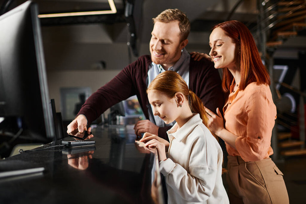 Drie mensen, een gelukkig gezin, verzameld rond een computerscherm, verdiept in wat ze zien. - Foto, afbeelding