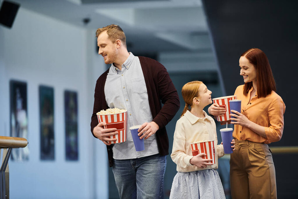 Счастливая семья, стоящая вместе, держа ведра попкорна. - Фото, изображение