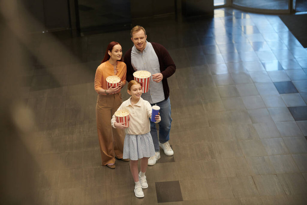 Muž, žena a malá holčička stojí při sobě, ztělesňují rodinnou sounáležitost a radost v kině. - Fotografie, Obrázek