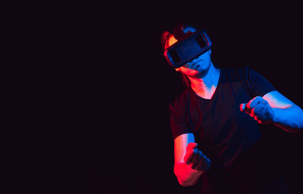 Ο νεαρός με τα γυαλιά εικονικής πραγματικότητας παίζει βιντεοπαιχνίδια. με χώρο για κείμενο - Φωτογραφία, εικόνα