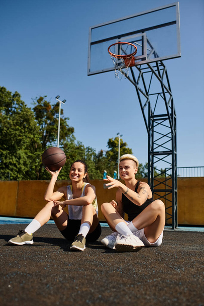 Dos mujeres jóvenes disfrutan de un juego de baloncesto en el suelo bajo el sol de verano. - Foto, imagen