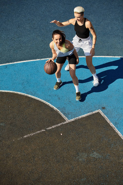 Μια γυναίκα που παίζει ενεργητικά μπάσκετ στο γήπεδο, επιδεικνύοντας τον αθλητισμό και την ομαδικότητα της σε ένα καλοκαιρινό παιχνίδι. - Φωτογραφία, εικόνα